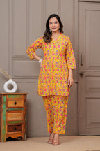 Woman wearing a yellow and pink floral handblock print cotton co-ord set with a V-neck kurta and straight pants.