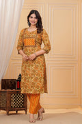 Woman wearing a mustard yellow floral handblock printed cotton kurta with orange zigzag pants set by Doriya Jaipur.
