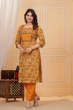 Woman wearing a mustard yellow floral handblock printed cotton kurta with orange zigzag pants set by Doriya Jaipur.